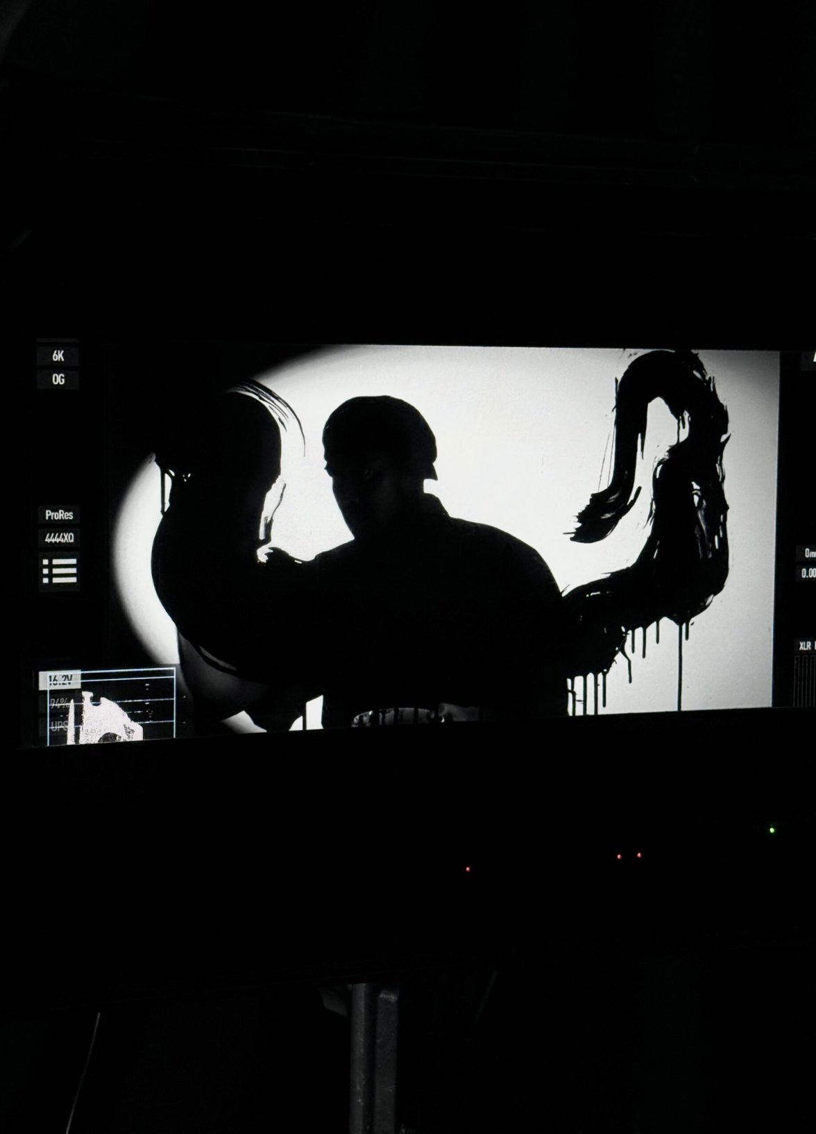 Silhouette of an artist forming expressive ink shapes against a backlit screen during the Mazda – Cinematic reveal of the Mazda 6E.