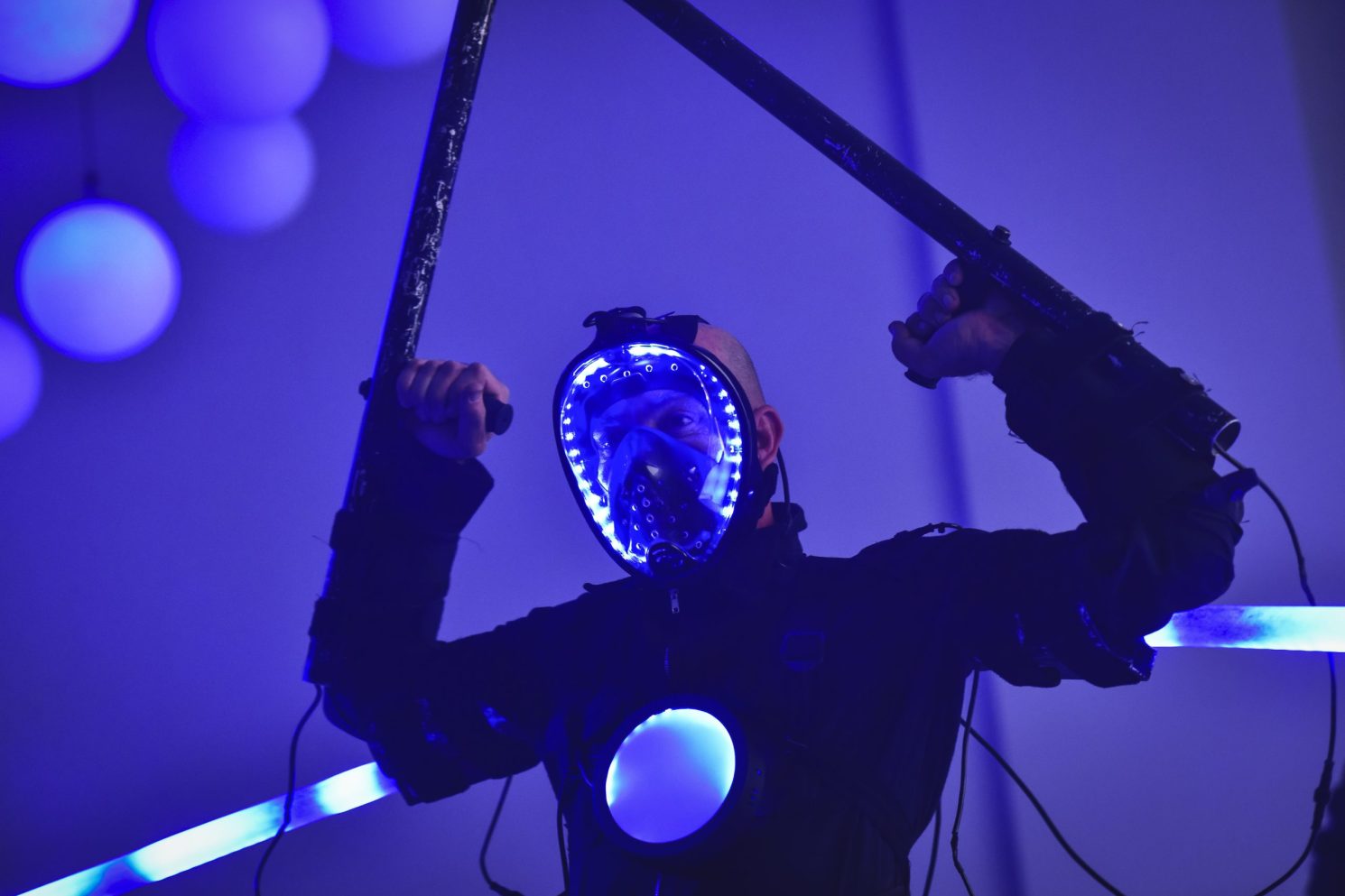 Performer wearing an illuminated LED mask and futuristic costume during the Conference in Buenos Aires – Immersive 360°, holding lighted props on stage.