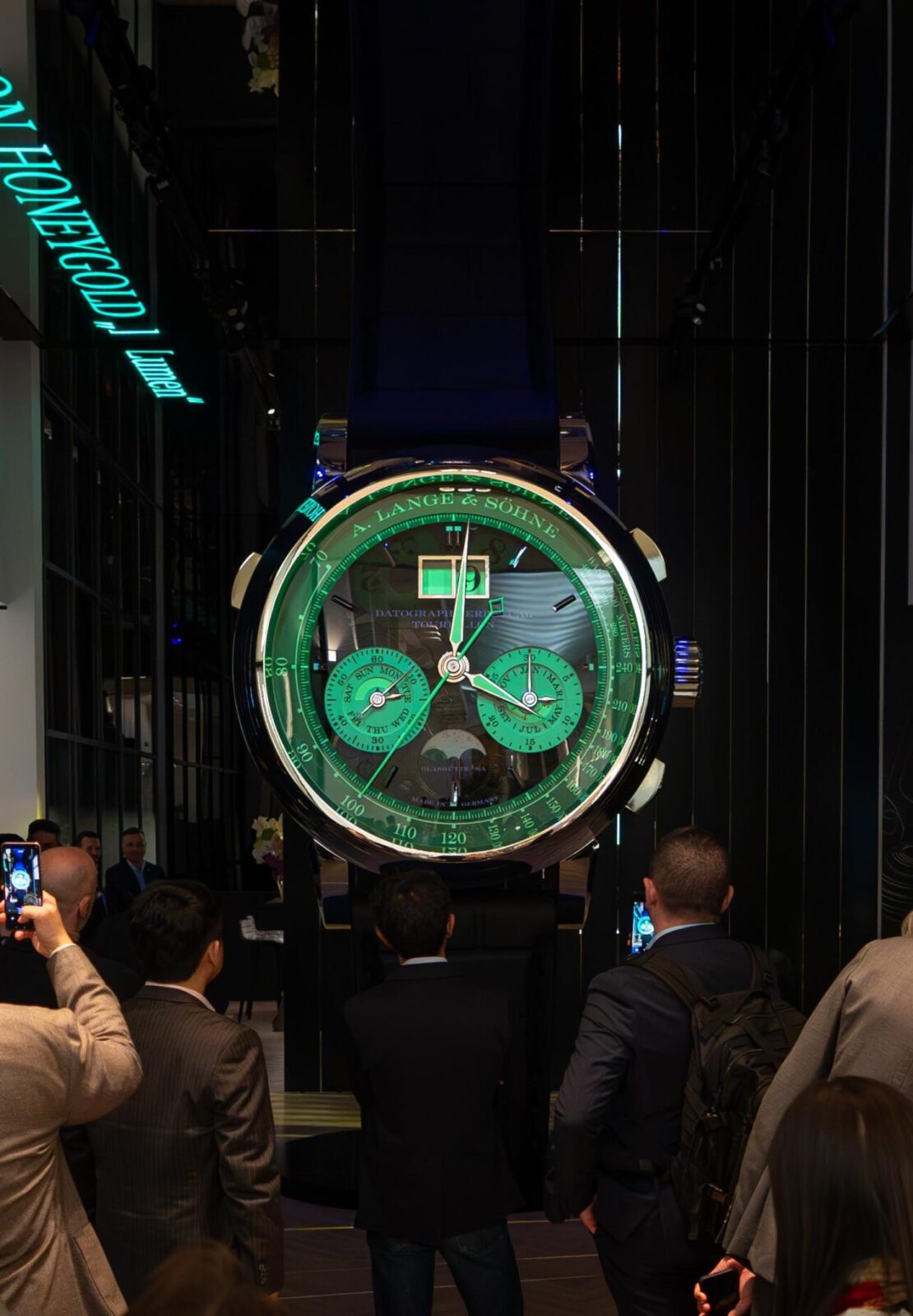 Visitors photographing a large-scale luxury watch installation inside a brand pavilion during Watches & Wonders – Geneva International Watchmaking Exhibition.
